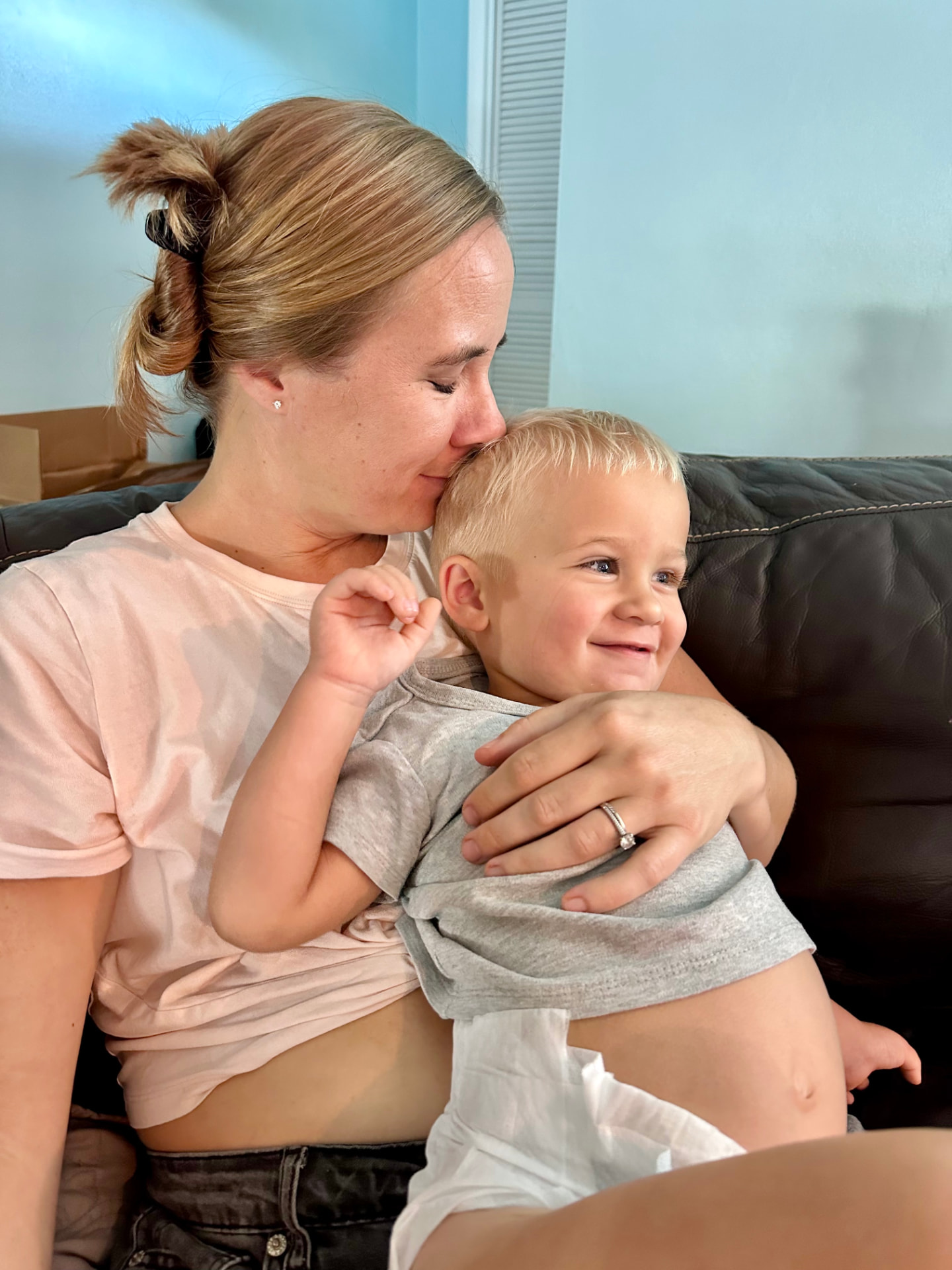 Johanna holding her young son close on the couch, cheek resting against his head